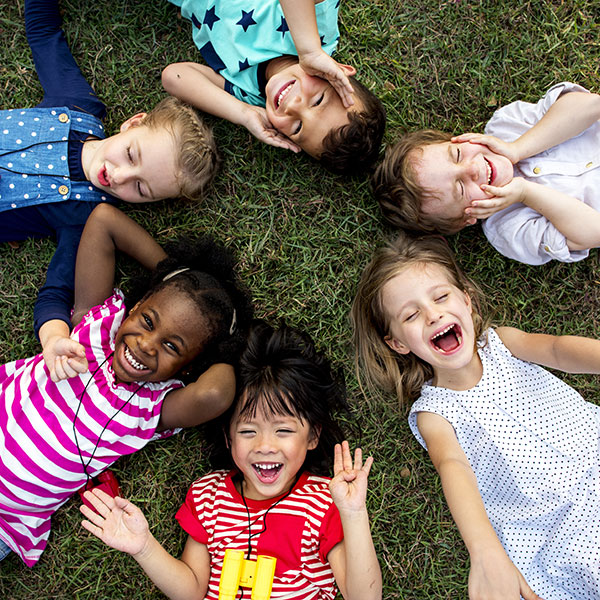 ChildrenSmilinginGrass Six children laying in the grass smiling.